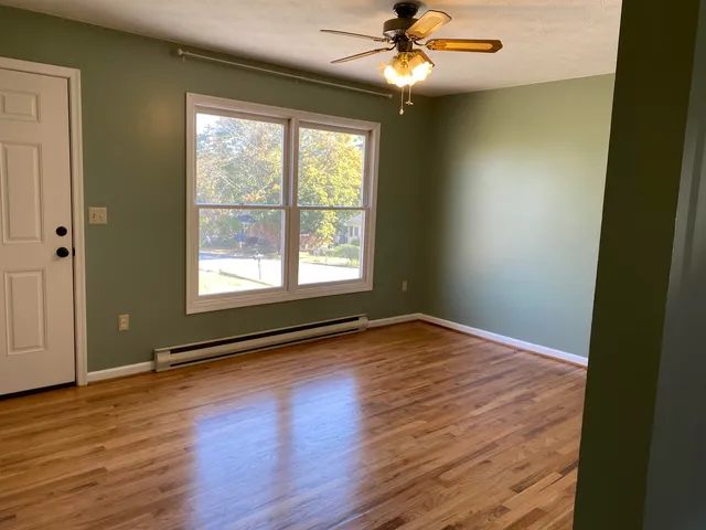 a view of an empty room with wooden floor and a window