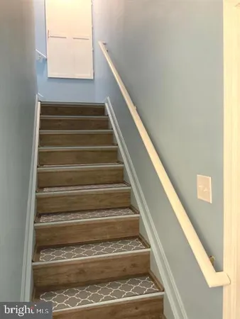 a view of a hallway with wooden floor and a bathroom