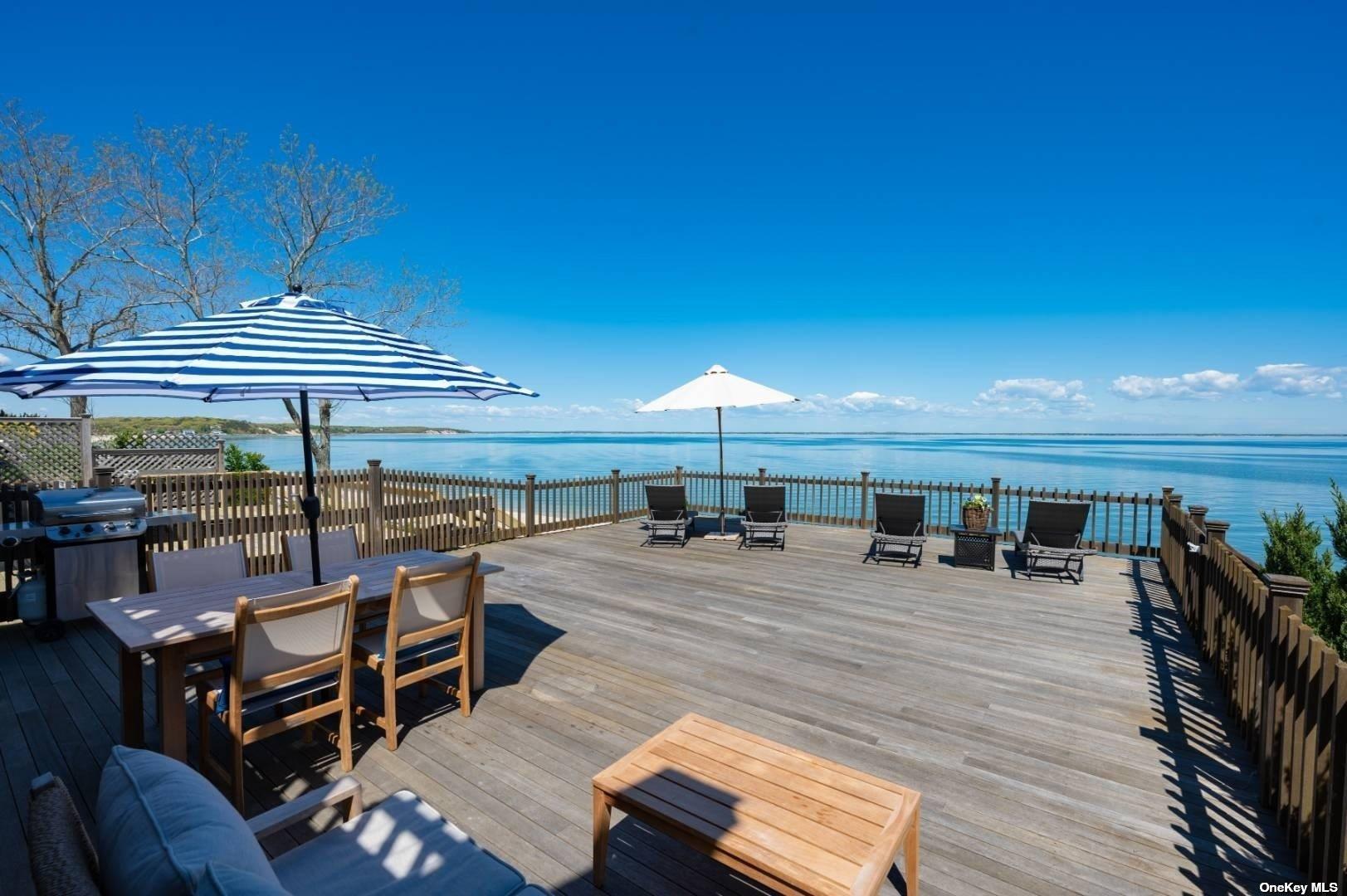 23 A Oakhurst Road Hampton Bays, NY 11946 - Photo 5 of 16 a view of a patio with dining table and chairs under an umbrella with wooden floor