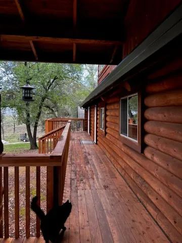 a balcony with wooden floor outdoor seating and yard in back