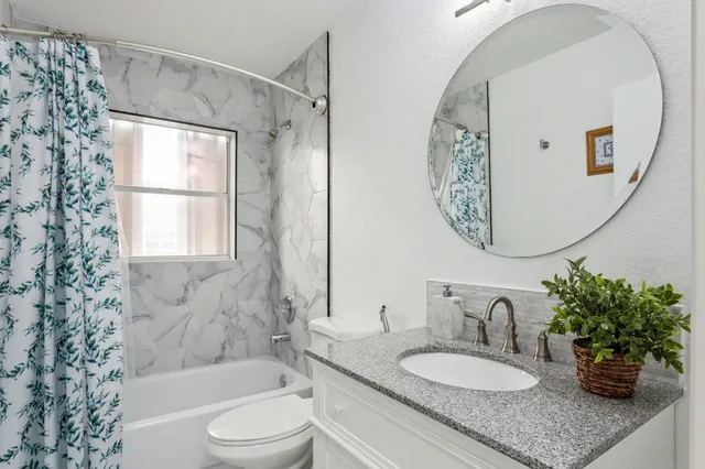 a bathroom with a granite countertop sink toilet a mirror and shower