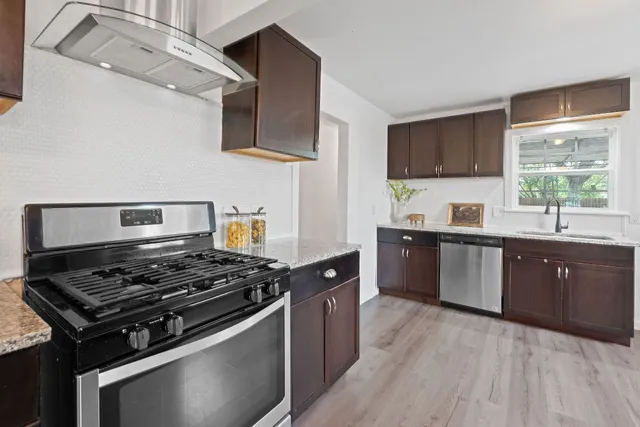 a kitchen with stainless steel appliances a sink dishwasher stove and oven