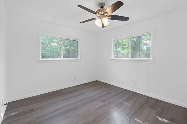 a view of an empty room with wooden floor and a window