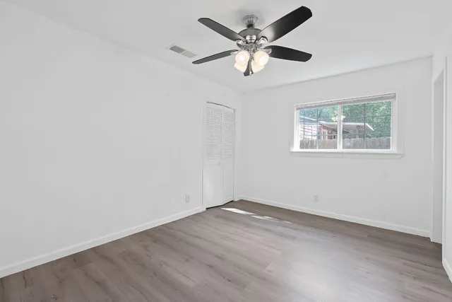an empty room with wooden floor and windows