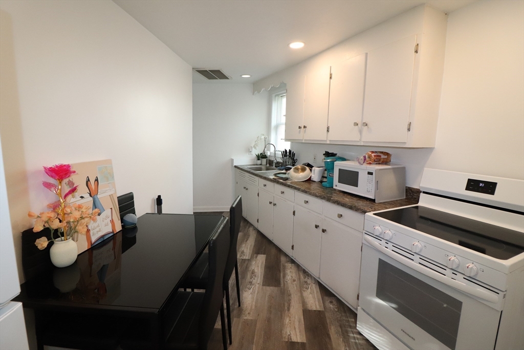 11 Palmer Street Fall River, MA 02724 - Photo 20 of 34 a kitchen with cabinets a sink dishwasher and a stove with wooden floor