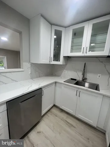 a kitchen with granite countertop a sink cabinets and wooden floor