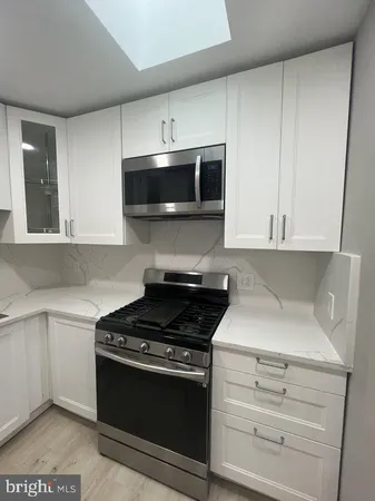 a kitchen with white cabinets and stainless steel appliances