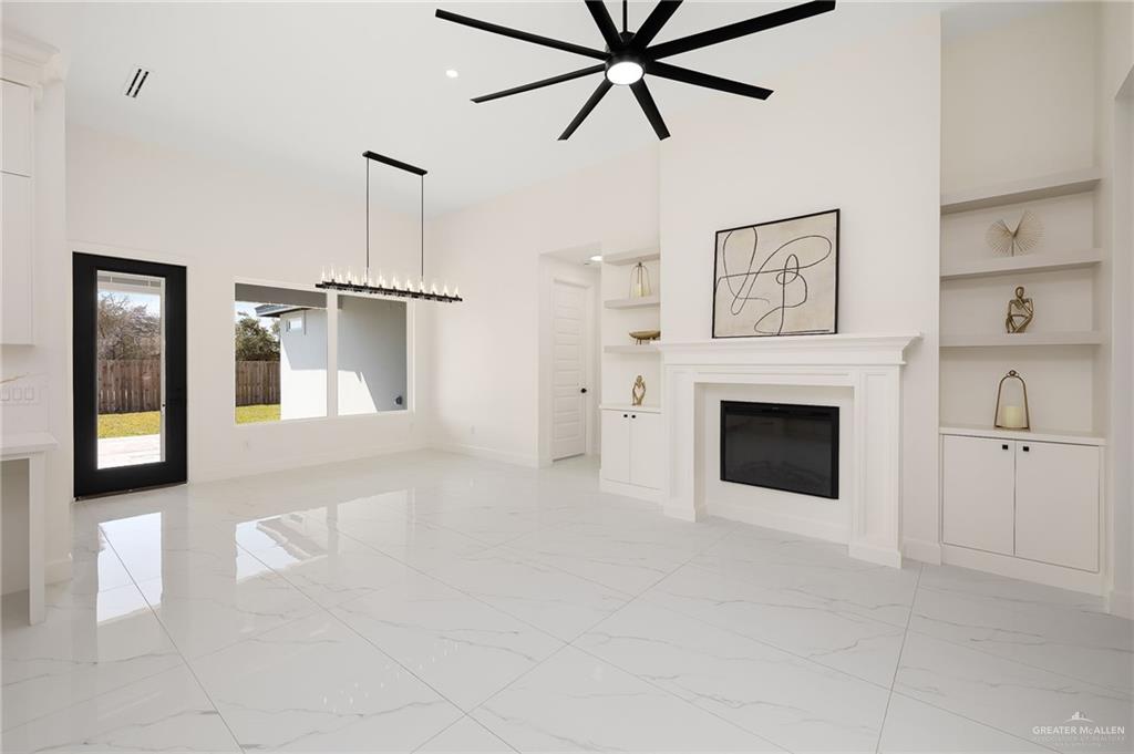 901 Azalea Street Mission, TX 78573 - Photo 10 of 29 Living room featuring light porcelain finish flooring, ceiling fan, a glass covered fireplace, and built in features
