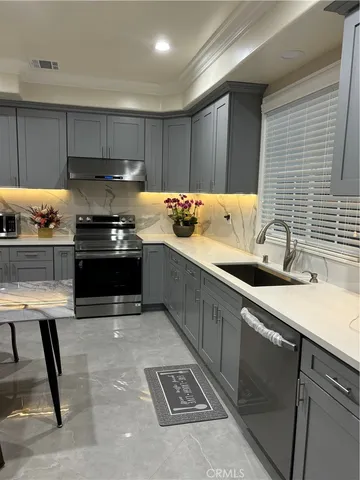 a kitchen with stainless steel appliances a stove a sink and a refrigerator