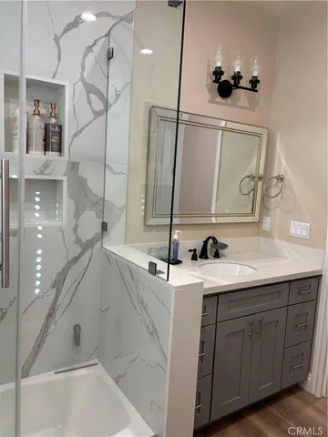 a bathroom with a sink and mirror with bathtub