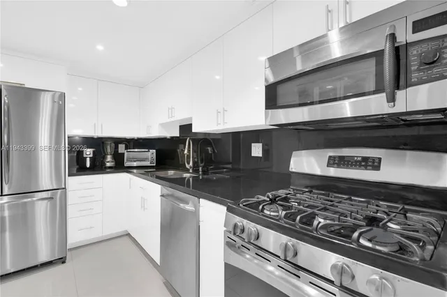 a kitchen with stainless steel appliances granite countertop a sink a stove and a refrigerator