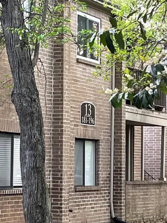 a view of a brick house with large windows and a large tree