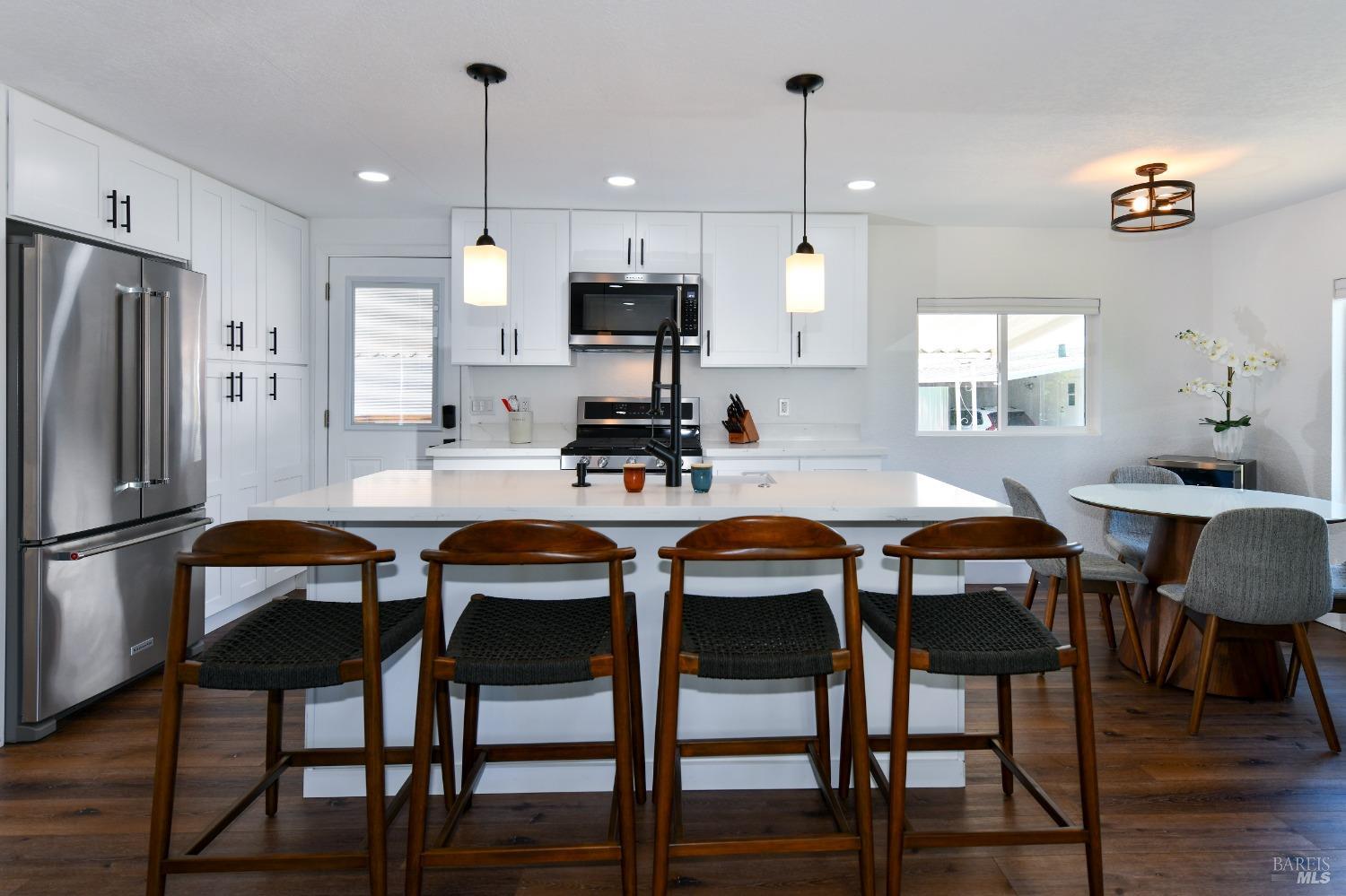 a kitchen with stainless steel appliances a dining table chairs refrigerator and microwave