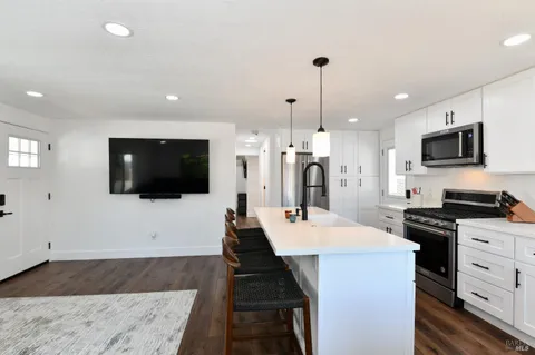 a large kitchen with stainless steel appliances kitchen island granite countertop a sink dishwasher a stove and a refrigerator with wooden floor