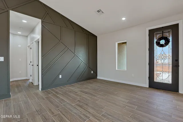 a view of an empty room with window and wooden floor