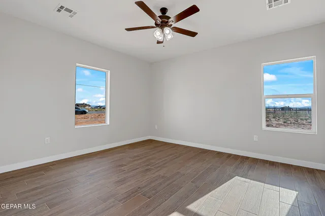 an empty room with wooden floor and windows