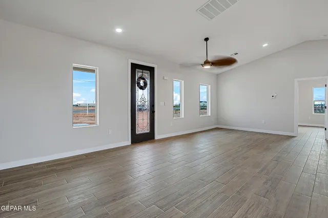 a view of an empty room with window and wooden floor