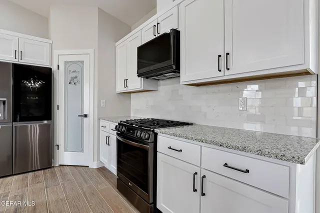 a kitchen with white cabinets and black appliances