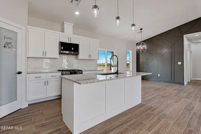 a kitchen with cabinets stainless steel appliances and wooden floor