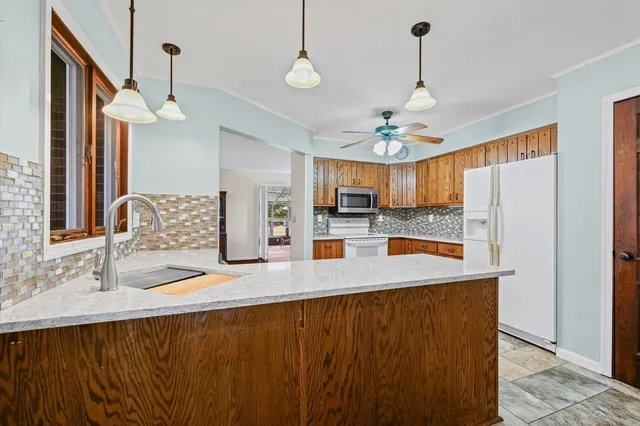 a kitchen with stainless steel appliances granite countertop a refrigerator a sink dishwasher a stove and a dining table with wooden floor