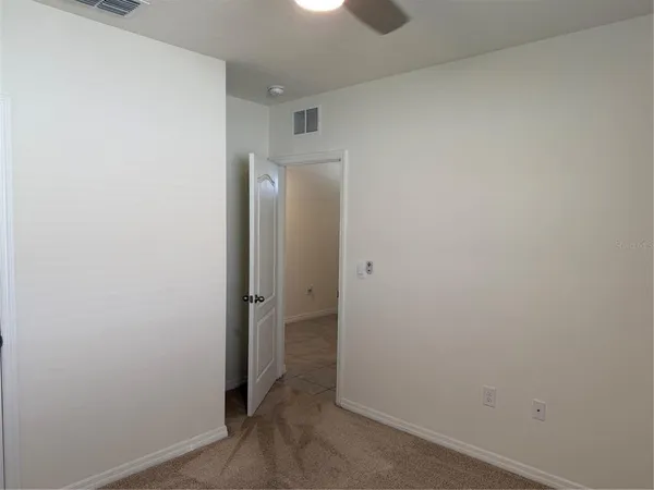 an empty room with a window and ceiling fan