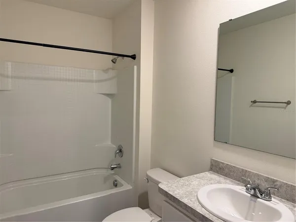 a bathroom with a granite countertop sink a mirror and shower