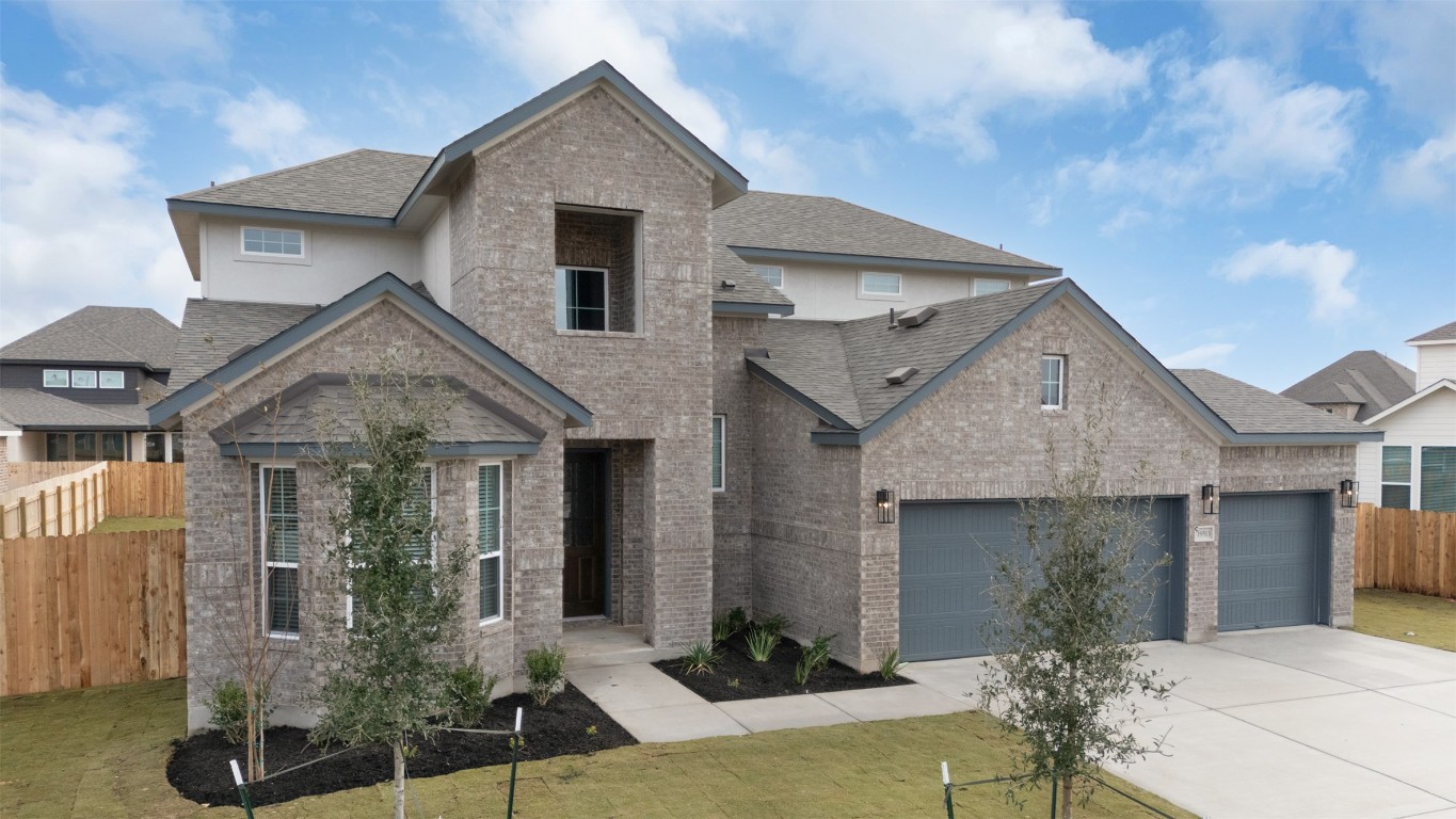 19513 Domino Champ Road Pflugerville, TX 78660 - Photo 2 of 28 View of front of property with brick siding, driveway, a garage, and roof with shingles