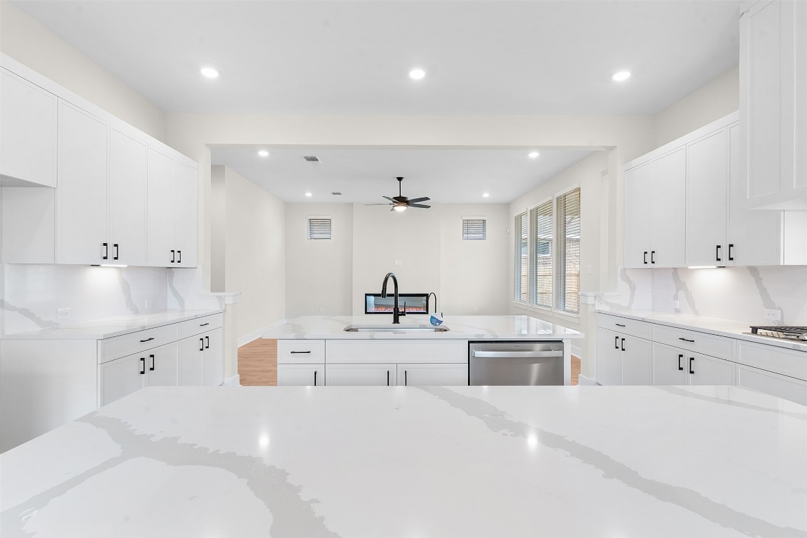 19513 Domino Champ Road Pflugerville, TX 78660 - Photo 10 of 28 a large white kitchen with kitchen island a sink stainless steel appliances and cabinets