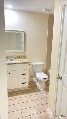a bathroom with a granite countertop toilet sink and mirror
