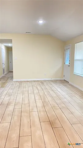 en empty room with wooden floor and natural light