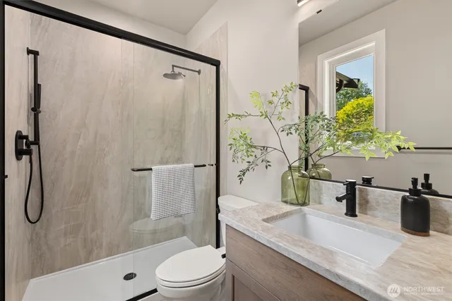 a bathroom with a granite countertop sink toilet and shower