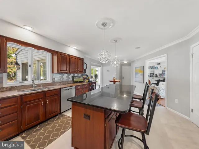 a kitchen with stainless steel appliances granite countertop a sink a counter top space cabinets and living room view