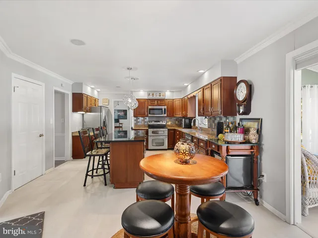 a kitchen with stainless steel appliances kitchen island granite countertop a sink a stove a dining table and chairs
