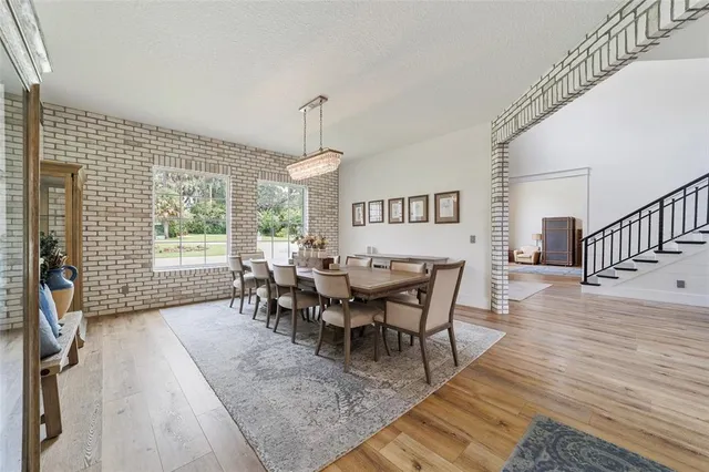 a dining room with wooden floor a chandelier a glass table and windows