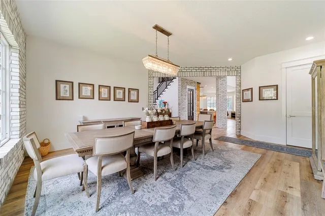 an open kitchen with granite countertop a stove a sink a dining table and chairs with wooden floor