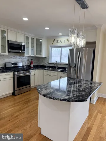 a kitchen with granite countertop a stove a sink and a microwave