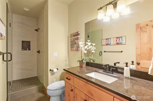 a bathroom with a granite countertop sink a toilet a mirror and shower