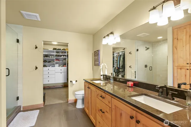 a spacious bathroom with a granite countertop double vanity sink a mirror and a shower