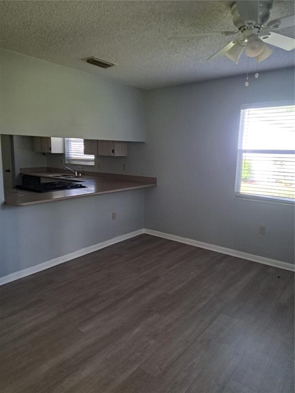 5618 Rosewall Circle Leesburg, FL 34748 - Photo 7 of 29 an empty room with wooden floor and kitchen view