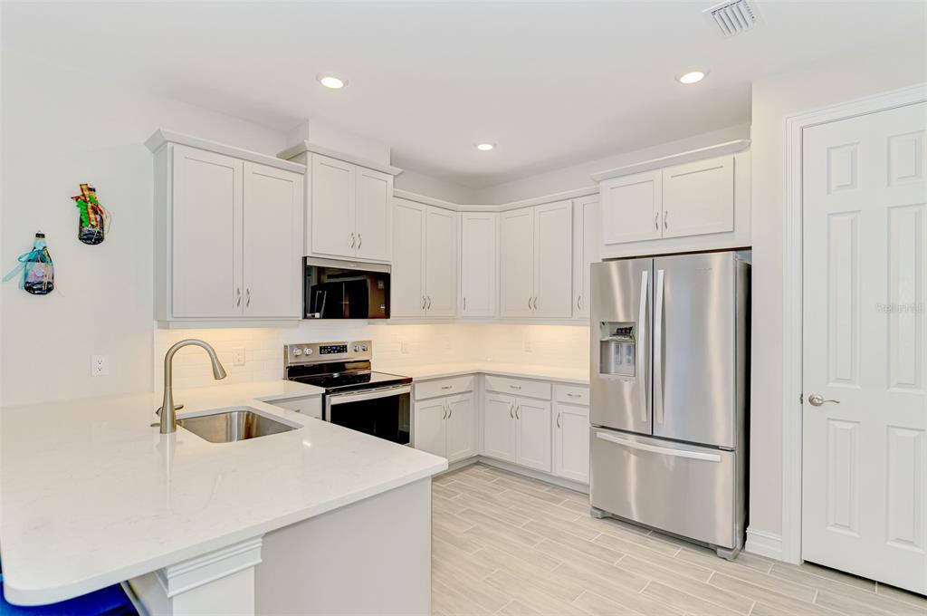 387 Ibiza Loop Venice, FL 34292 - Photo 17 of 60 a kitchen with a refrigerator a stove top oven a sink and white cabinets