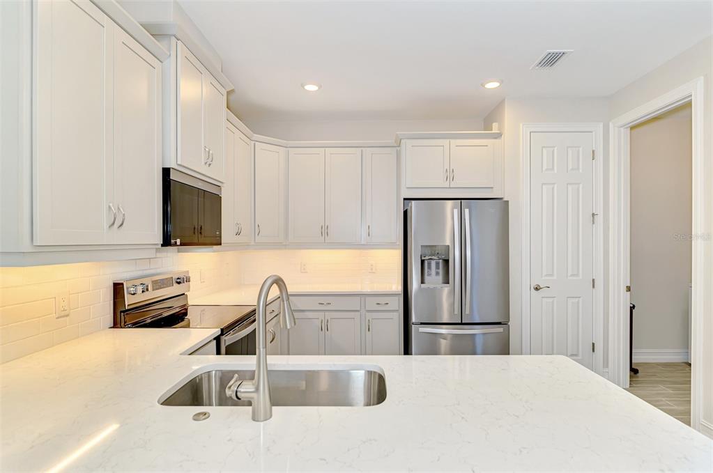 387 Ibiza Loop Venice, FL 34292 - Photo 18 of 60 a kitchen with stainless steel appliances granite countertop a refrigerator sink and stove