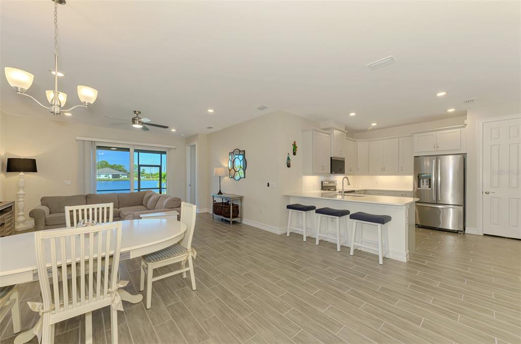 387 Ibiza Loop Venice, FL 34292 - Photo 7 of 60 a kitchen with stainless steel appliances kitchen island granite countertop a stove a sink a dining table and chairs with wooden floor
