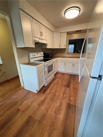 a kitchen with granite countertop a sink a stove top oven and cabinetry