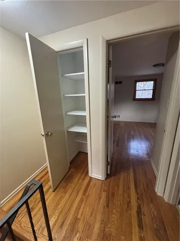 a view of a hallway with wooden floor and closet