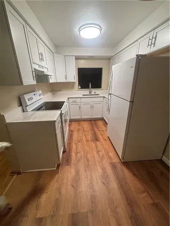 a kitchen with a refrigerator a stove top oven a counter space and wooden floor