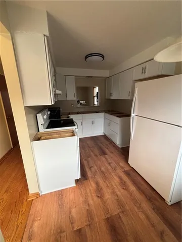 a kitchen with a sink a refrigerator and wooden floor