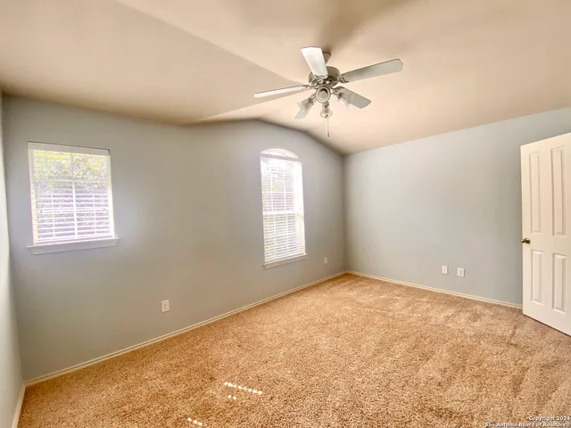 a view of an empty room with window and chandelier fan