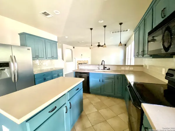 a kitchen with stainless steel appliances a sink a stove a refrigerator a center island and a stove