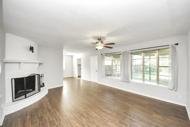 a view of an empty room with wooden floor and a fireplace