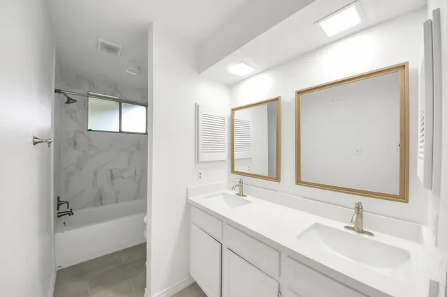 a bathroom with a bathtub shower sink and mirror